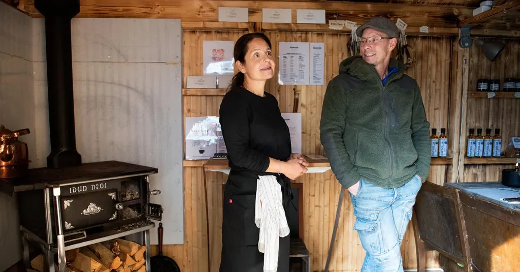Louise och Henrik i den varma trästugan med vedspis och handskrivna menylappar på väggen